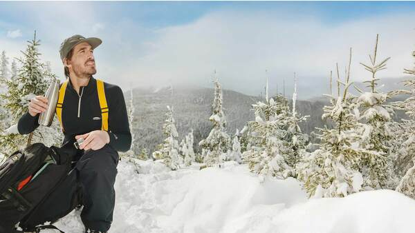 Man wearing a base layer taking a water break in the mountains