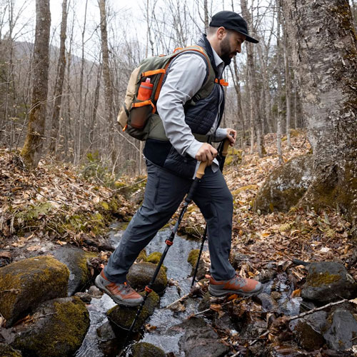 A springtime hiker crossing a flowing stream during a trail hike
