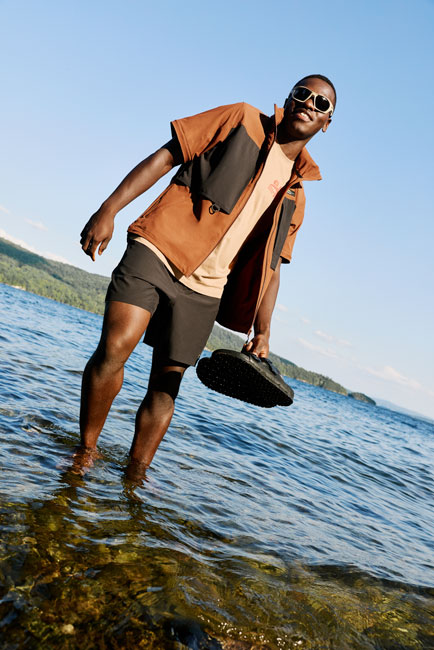 Homme marchant dans l’eau peu profonde par temps ensoleillé, habillé de vêtements de plein air Chlorophylle.