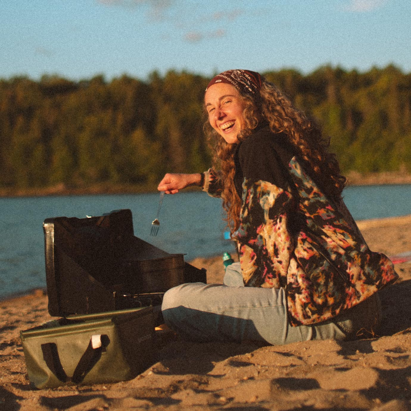Femme qui cuisine sur la plage en bordure d'un lac